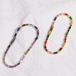 Elegant gold and silver rainbow zircon bracelets with colorful gemstones on white fabric