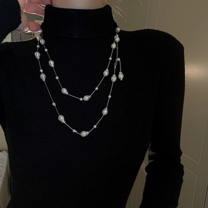 Detail view of double-layer necklace with irregular pearls on black knitwear