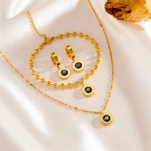 Golden Roman numeral jewelry set with black stones on elegant white silk backdrop