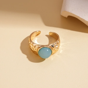 Détail d'une bague dorée réglable avec texture martelée et pierre bleu ciel arrondie