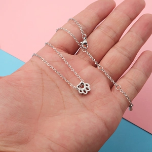 Stainless steel pet paw pendant necklace with adjustable chain shown in a hand