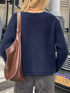 Détail arrière d'un pull en maille épaisse bleu marine porté avec un sac à bandoulière en cuir