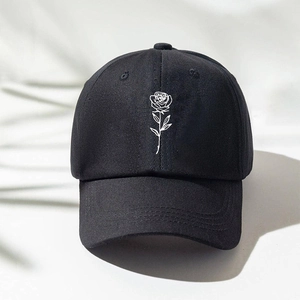 Close-up of a black cotton baseball cap featuring detailed white rose floral embroidery
