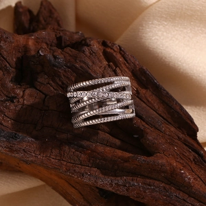 Macro detail of multi-layer crisscross silver ring with zircons on dark wood texture