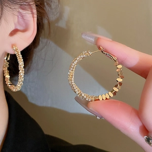 Vue détaillée des créoles dorées rondes avec incrustation de zircons et de sequins