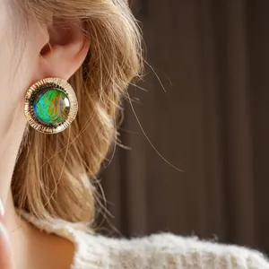 Vintage round stud earring with iridescent opal-like stone and golden pleated metal frame