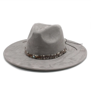 Detail of grey wide brim fedora hat featuring decorative band with evil eye ornament
