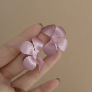 Dettaglio degli orecchini a fiore rosa con finitura in metallo opaco e verniciato