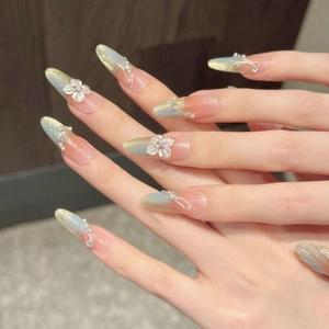 Detail showing long almond press-on nails with 3D floral accents and pearls