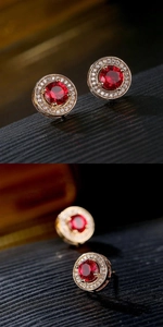 Macro shot of circular stud earring featuring a red gemstone and gold-tone finish