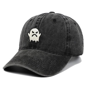 Detailed close-up of ghost embroidery on washed black denim baseball cap fabric