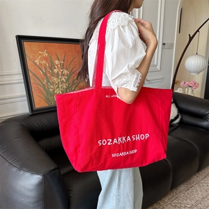 Seitenansicht der großen roten Segeltuchtasche mit weißem Stickmotiv am Modell getragen