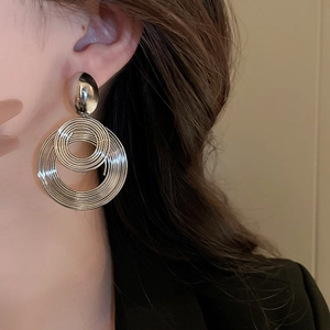 Close-up of double concentric silver metal geometric earrings on a female model