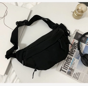 Detail view of black canvas chest bag with adjustable strap and casual lifestyle props