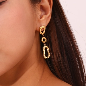 Détail de boucles d'oreilles géométriques martelées plaquées or 18 carats sur un mannequin
