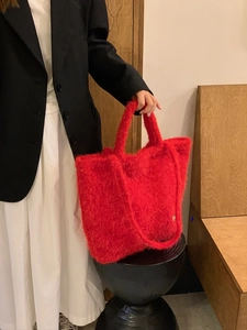 Dettaglio della borsa tote in peluche rossa con morbida trama indossata da una modella