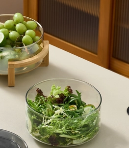 Close-up of glass salad bowl with bamboo stand showing fresh fruit and clear texture