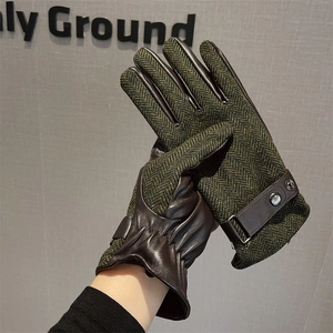 Detail of winter warm gloves showing green herringbone fabric and brown leather textures