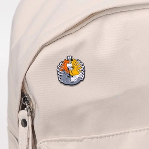 Cartoon cat skeleton heart enamel pin displayed on a beige canvas backpack strap