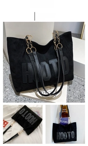 Detail of black suede tote bag with HOOTO embossing and metal chain shoulder strap
