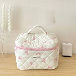 Quilted cotton makeup bag with pink bow pattern, top handle and brand logo patch