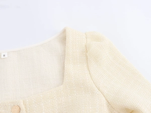 Détail du haut en tweed beige avec col carré et boutons dorés texturés
