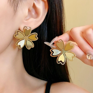 Close-up of elegant gold hollow flower stud earrings worn by a model in warm light