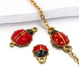 Macro detail of gold-plated ladybug pendants with red enamel finish for jewelry DIY