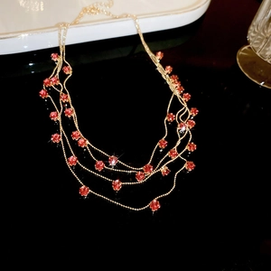 Macro detail of triple-layer gold necklace with sparkling red round zircon pendants