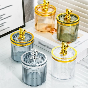 Vertical striped glass jars with metal bear lids in various colors on a marble surface