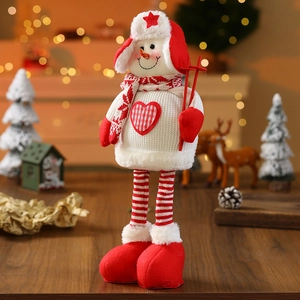 Detail of a plush Christmas snowman doll with heart ornament on a festive wooden surface
