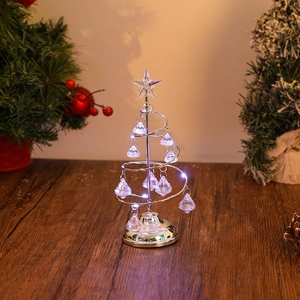 Close-up of a lit metal spiral Christmas tree lamp with crystal pendants and star top