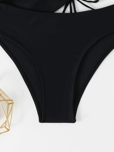 Detailed close-up of black high-cut bikini bottoms with stylish side cross-tie details