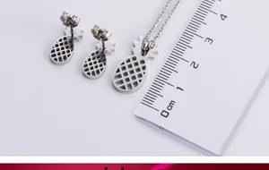 Detailed close-up of hollow pineapple pendant and stud earrings set in silver finish
