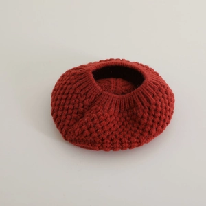 Gros plan d'un béret rouge en maille épaisse montrant les détails du tissu et du tissage