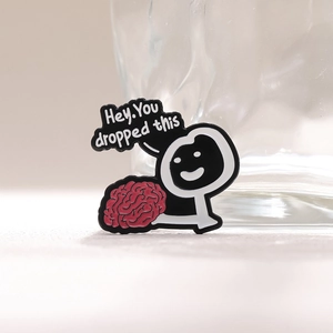 Creative enamel pin featuring a funny cartoon figure holding a red brain with text