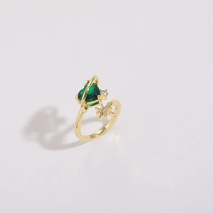 Close-up of gold planet ring with green heart gemstone and saturn ring detail
