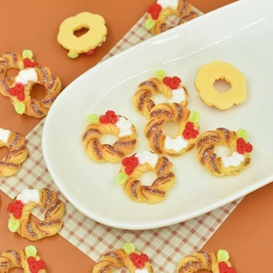 Miniature resin Christmas wreath donuts and tiny pastry models on a white ceramic plate