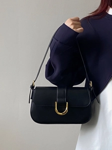 Detail of black matte leather shoulder bag with elegant golden U-shaped metal buckle