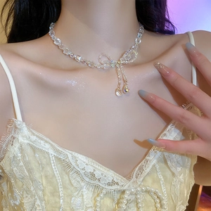 Detail shot of crystal beaded bow necklace with tassels worn on neck for women