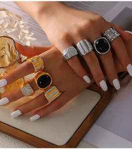 Close-up of gold and silver geometric rings with black stones and paved diamonds on hand