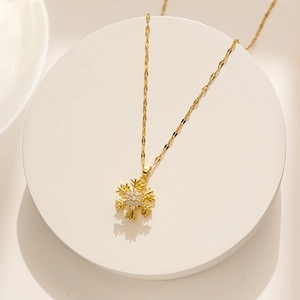 Close-up of a rotating gold snowflake pendant with zircon stones on a white stand