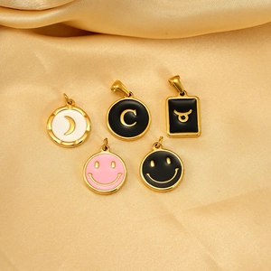 Detailed view of 18K gold plated charms with moon, letter C, and enamel smiley face motifs