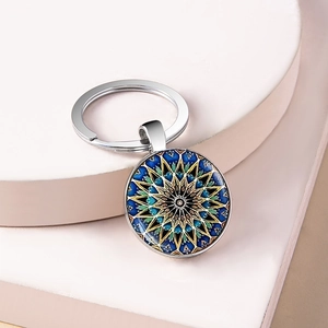 Close-up of a silver mandala keychain featuring a blue and yellow glass dome pendant
