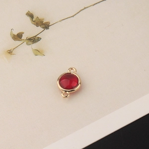 Macro view of gold-plated copper circular red crystal charm with double hanging loops