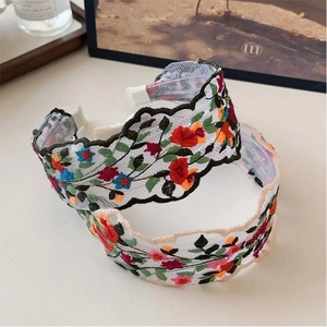 Detail of two floral lace headbands with intricate embroidery in dark and light colors