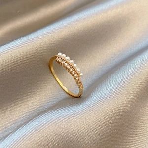 Close-up of golden ring featuring parallel white pearls and rows of sparkling zircons