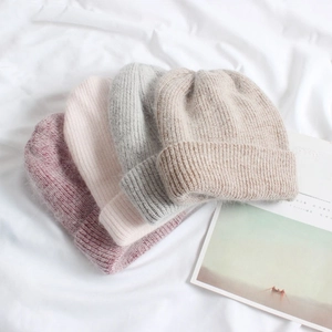Stack of four warm angora rabbit fur knit beanies in purple, pink, grey and beige