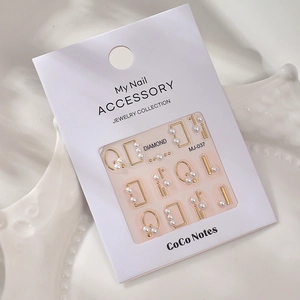 Detail of 5D pearl nail art stickers with gold frames and 3D relief on a white card