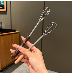 Close-up of mini stainless steel whisks with dark and light natural wooden handles